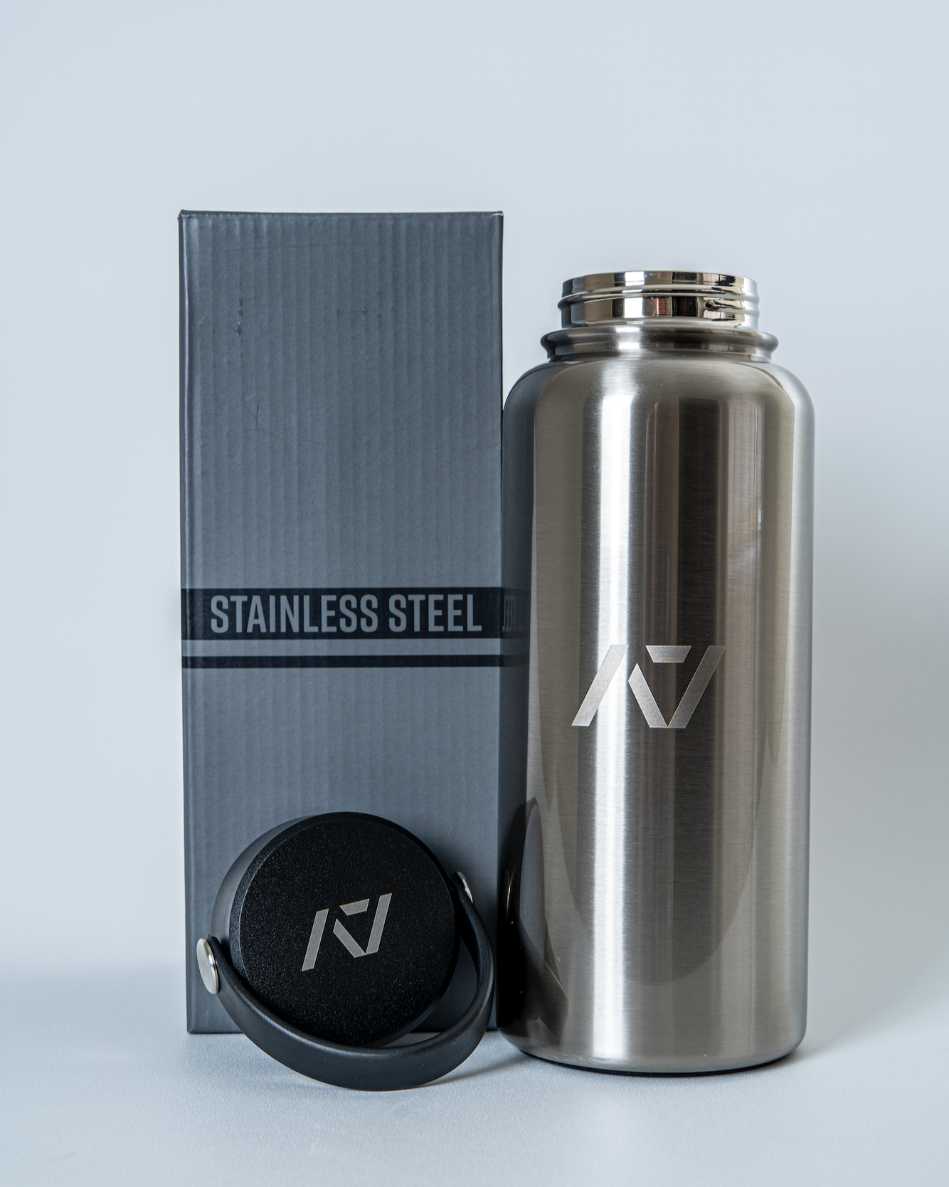 Stainless steel water bottle with cap and branded box on a light gray background