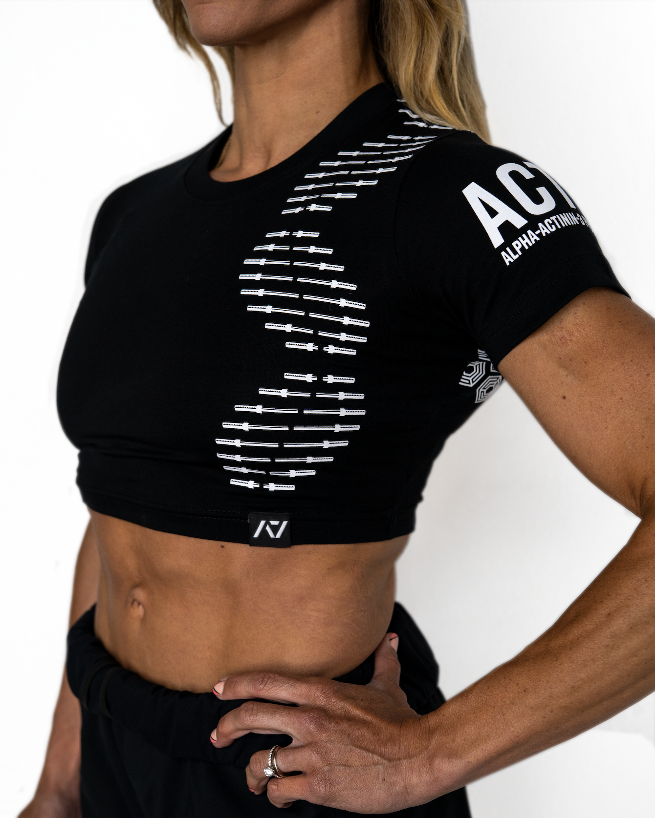 Person wearing a black athletic crop top with branding on a white background