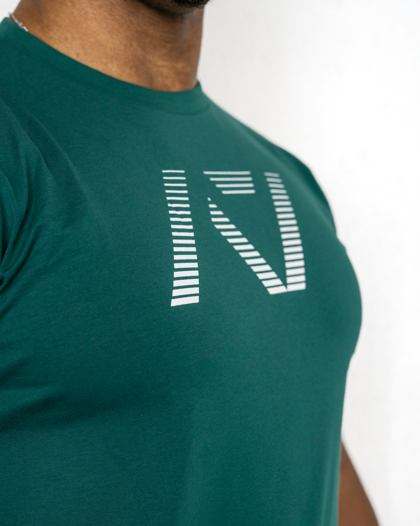Green t-shirt with a logo worn by a person on a white background