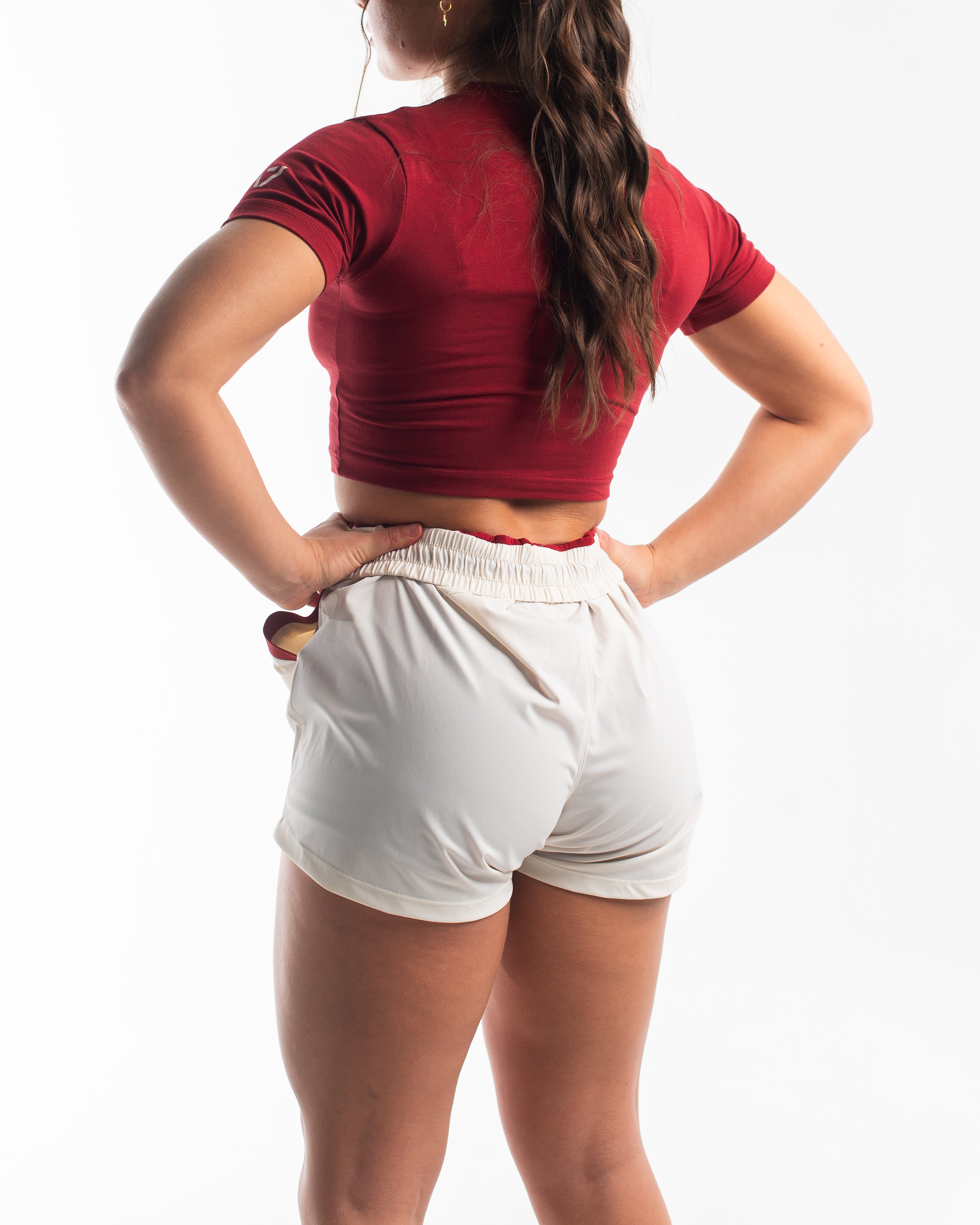 Back of female model wearing the ivory shorts with the red inner liner