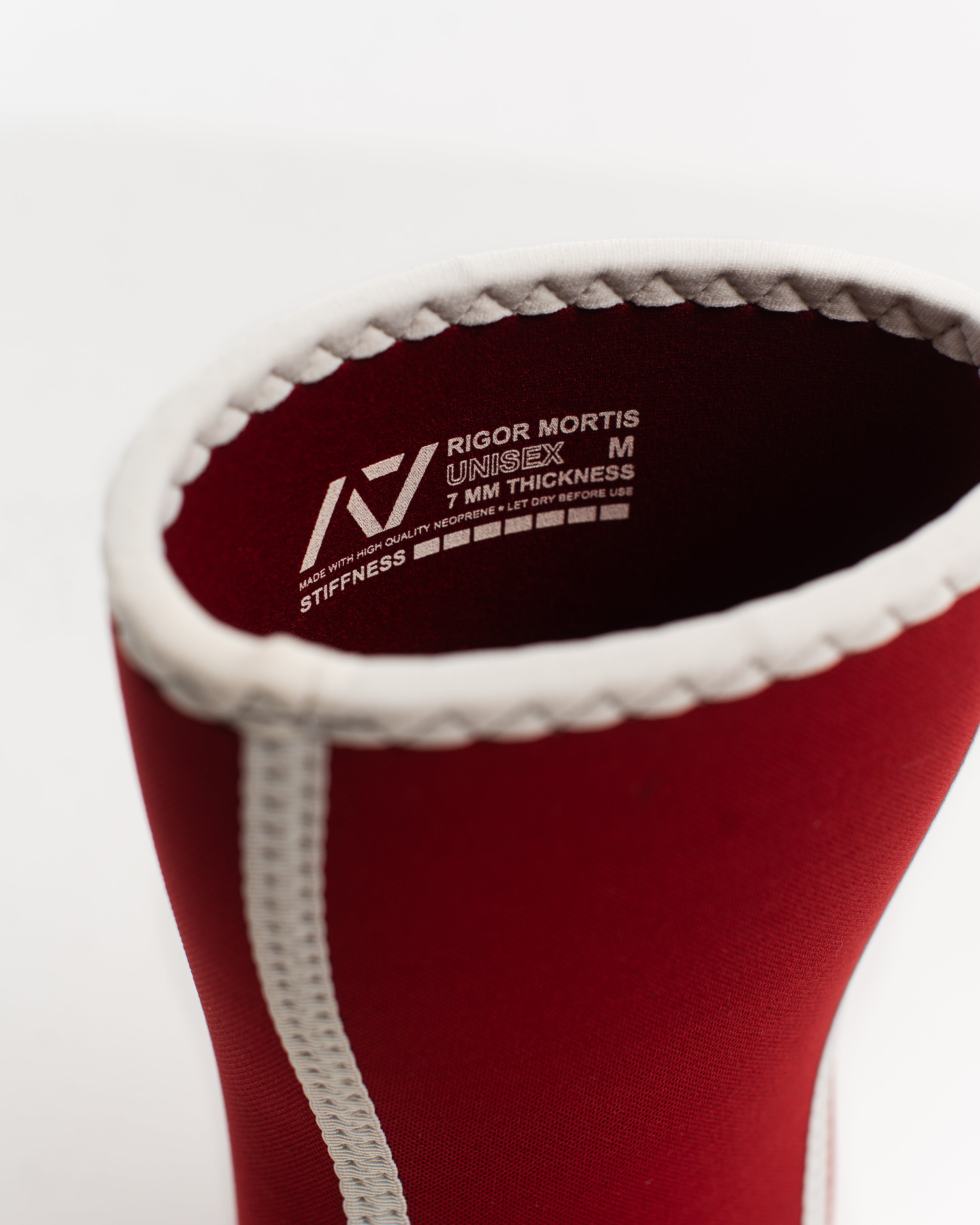 Red knee sleeve with red interior and branding text with sizing and stiffness level