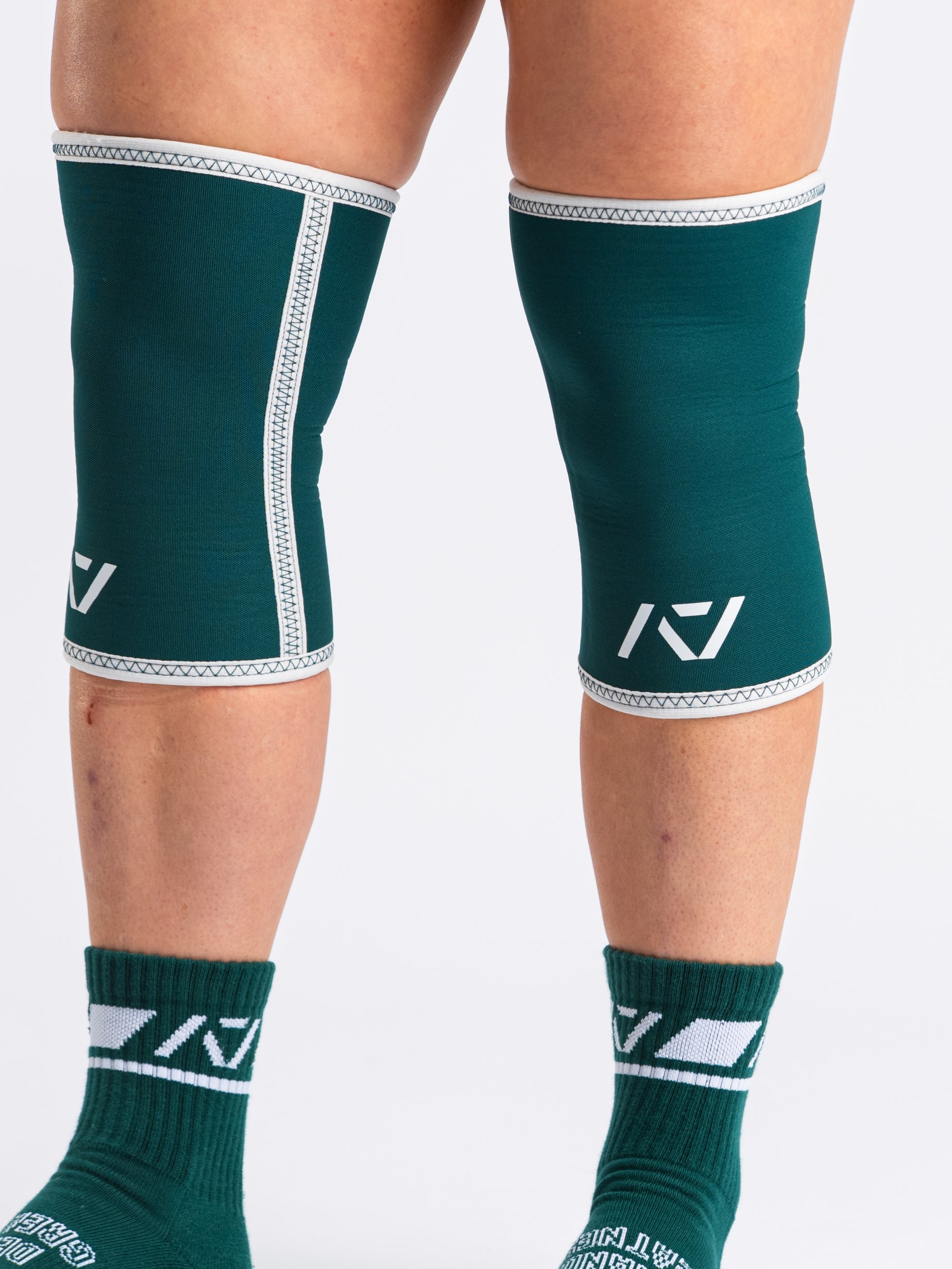 Side view of lifter executing stood with A7 Hourglass Knee Sleeves – Emerald Forás, highlighting snug fit and support during powerlifting.