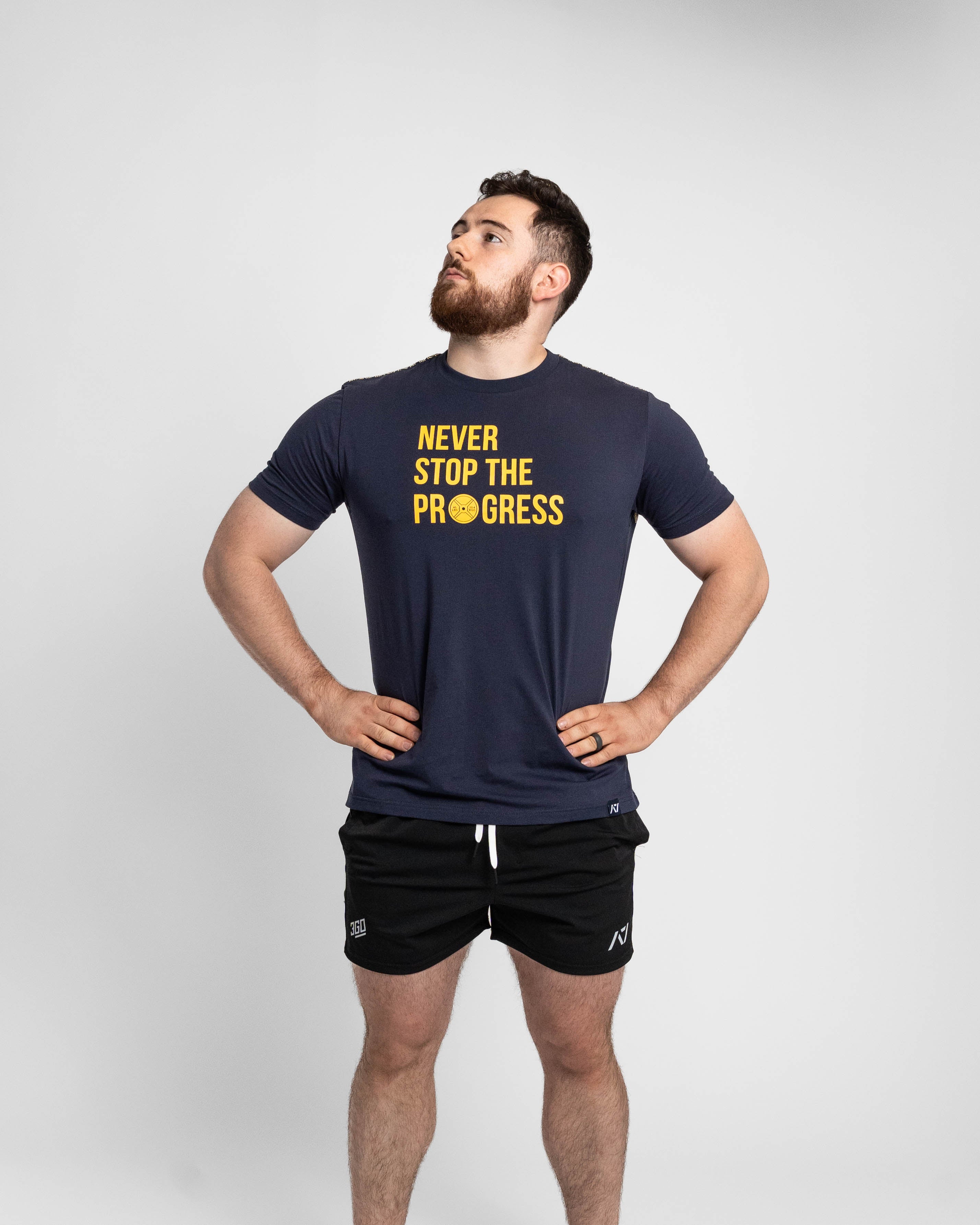 Man wearing a navy t-shirt with 'Never Stop The Progress' text on a white background
