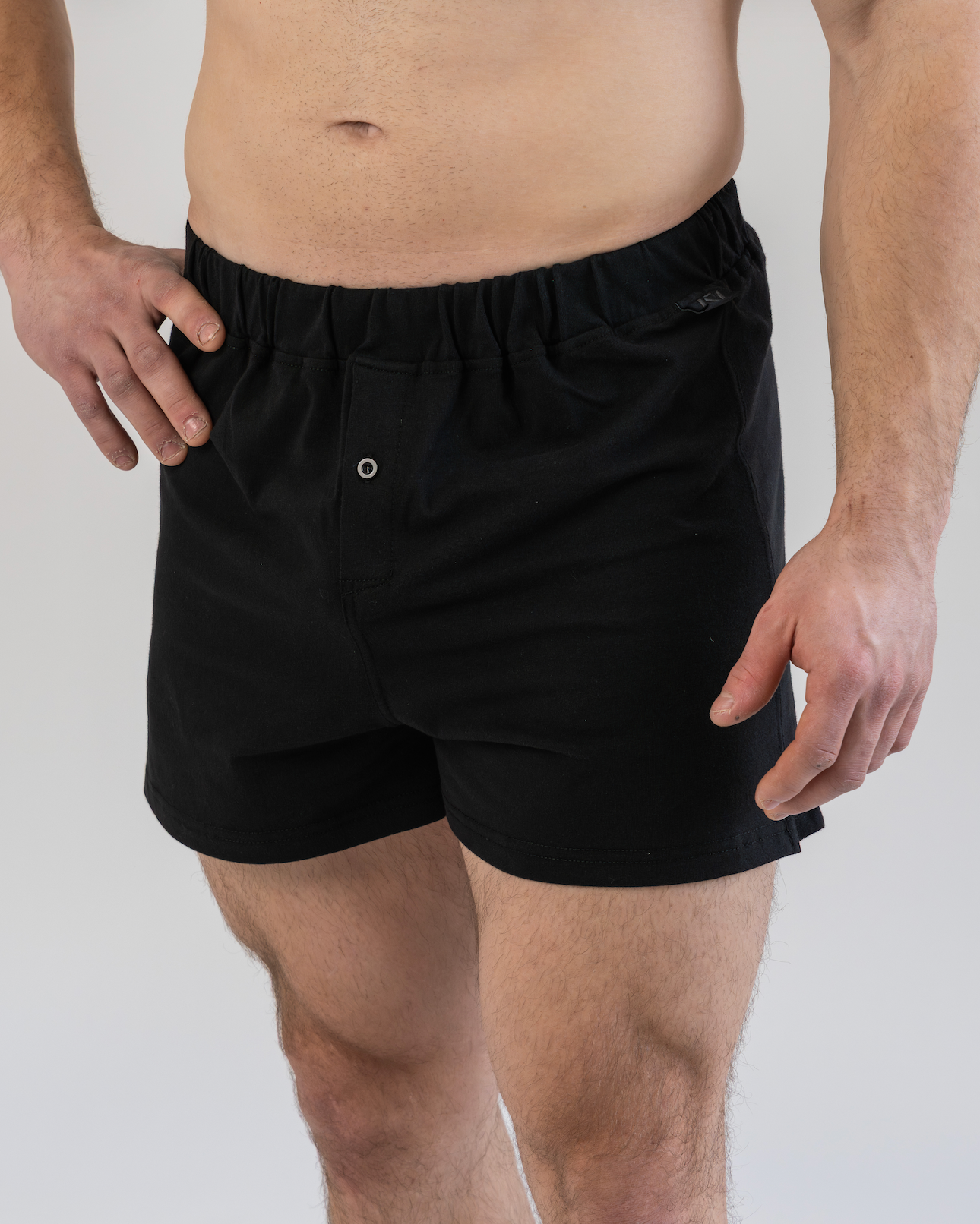 Person wearing black boxer shorts on a plain background