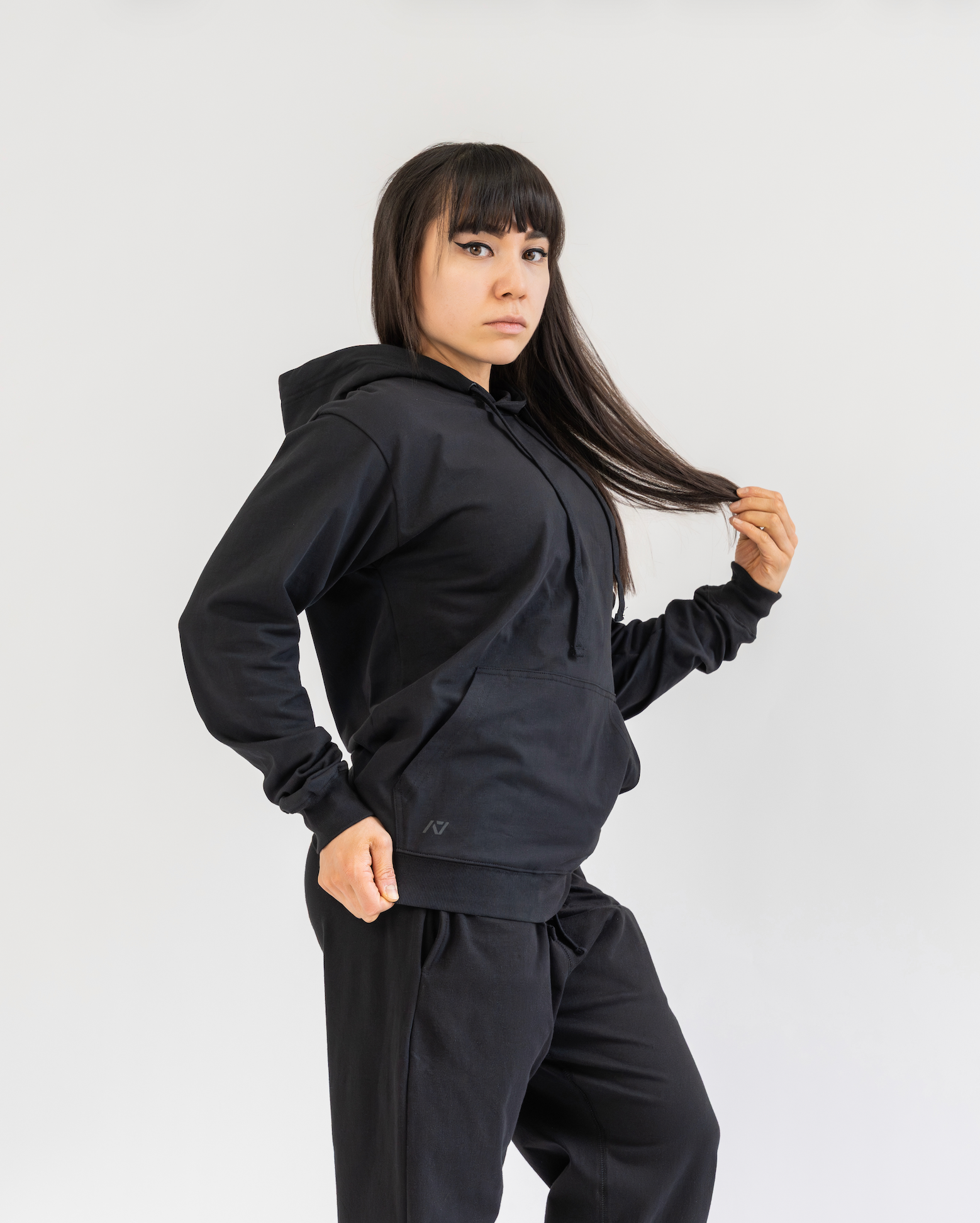 Person wearing a black hoodie and pants on a white background