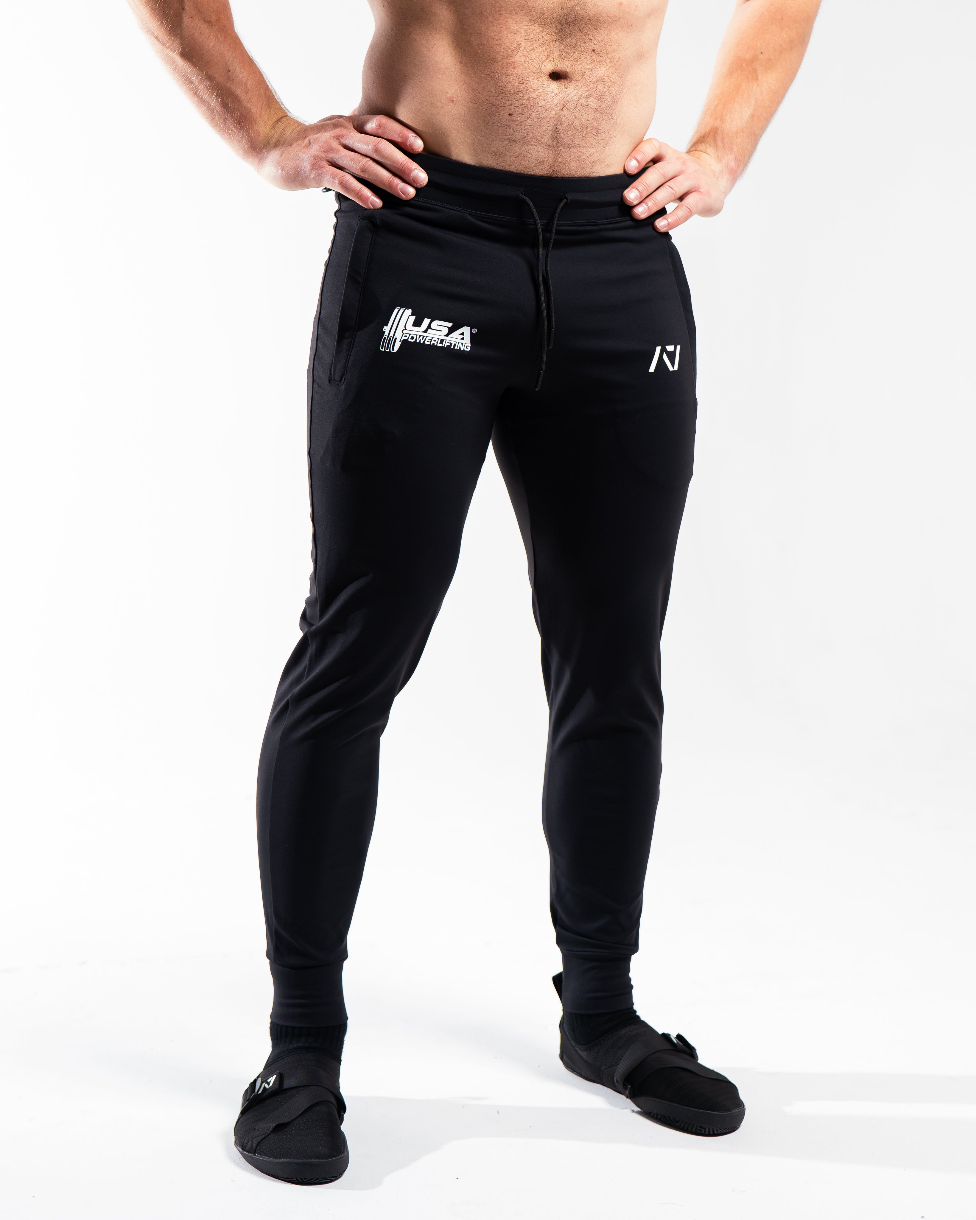 Front view of the USAPL Classic Defy Joggers showing zippered pockets, mid-rise waist, and logos.