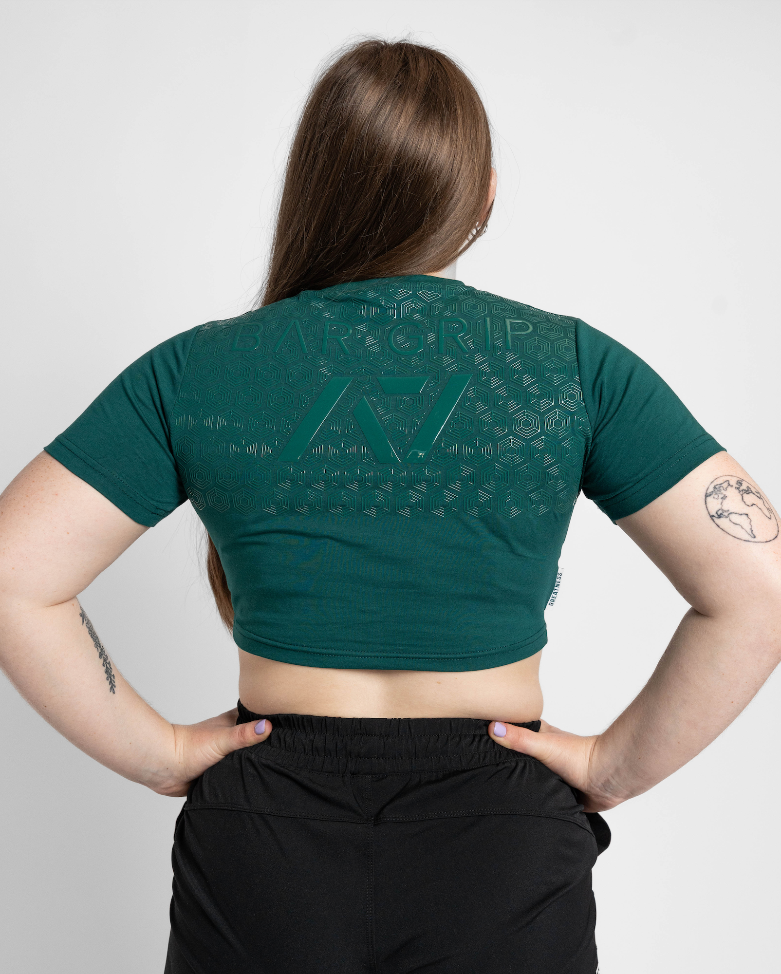 Person wearing a green crop top with a bar grip on a plain background